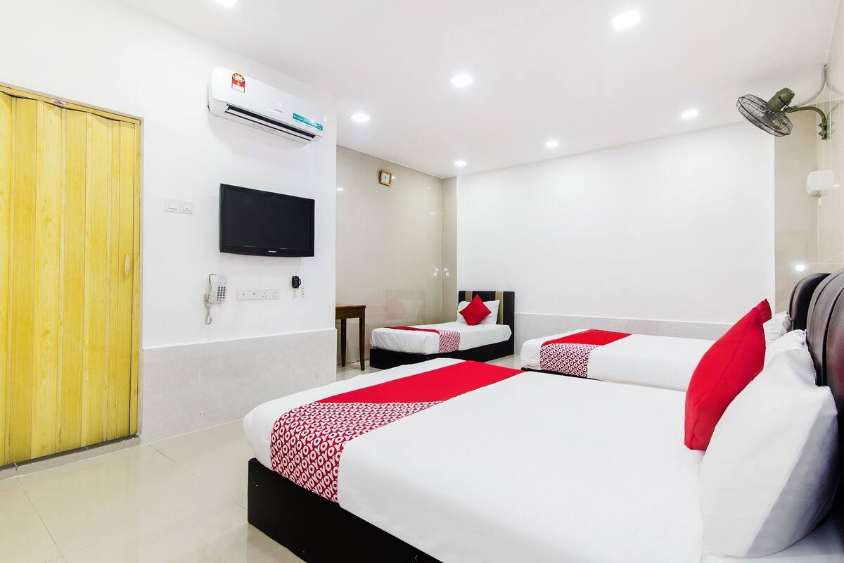 Ein Hotelzimmer mit zwei Betten, einem Fernseher, einer Klimaanlage und einer Holztür.