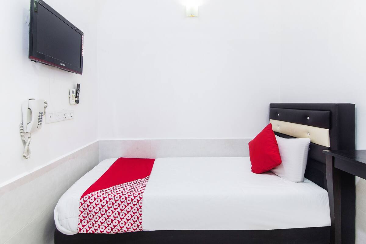 Ein Hotelzimmer mit Bett, Wandfernseher, Telefon und Lampenleuchte.