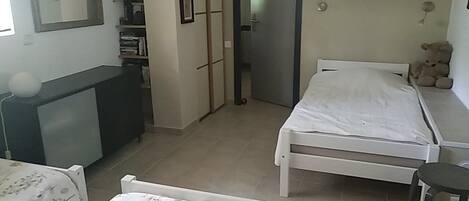 A bedroom with a bed, bedside table, and a teddy bear on a shelf.