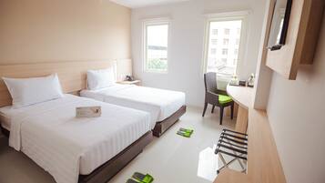 Ein Hotelzimmer mit zwei Betten, einem Schreibtisch, einem Stuhl und einem Fenster.