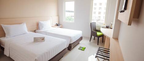Habitación de hotel con dos camas, un escritorio, una silla y un ventanal.