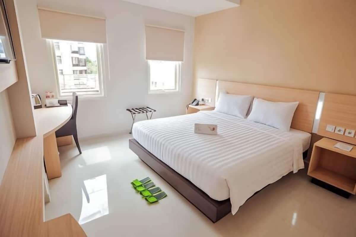 Una habitación de hotel moderna con una cama grande, mesitas de noche, un escritorio y una silla.