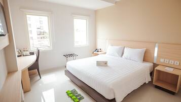 A modern hotel room with a large bed, a desk, and two windows.