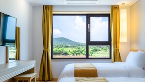 Una habitación de hotel con cama, escritorio y una ventana grande con cortinas.