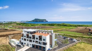 Un edificio moderno con varios pisos, una terraza en la azotea y un estacionamiento.