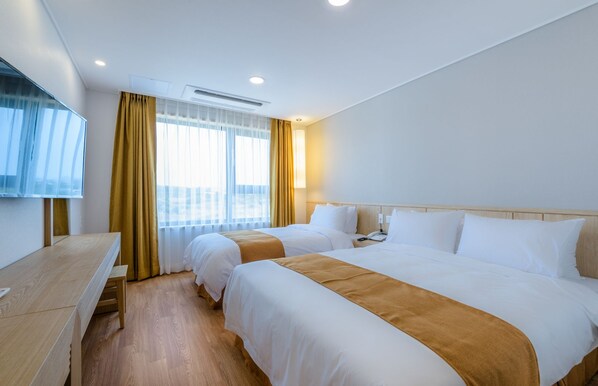A hotel room with two beds, a desk, and a TV. - Thira Hotel (Seogwipo)