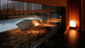 Ein modernes Interieur mit einer Glasabtrennung, einem Steinweg und einer Sitzgelegenheit mit Bänken.