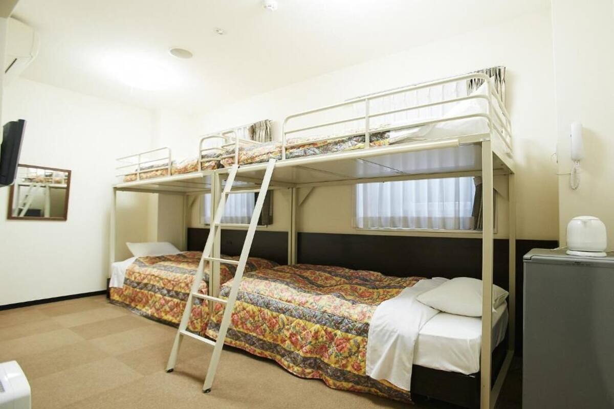 A bunk bed room with a ladder, a desk, and a telephone.