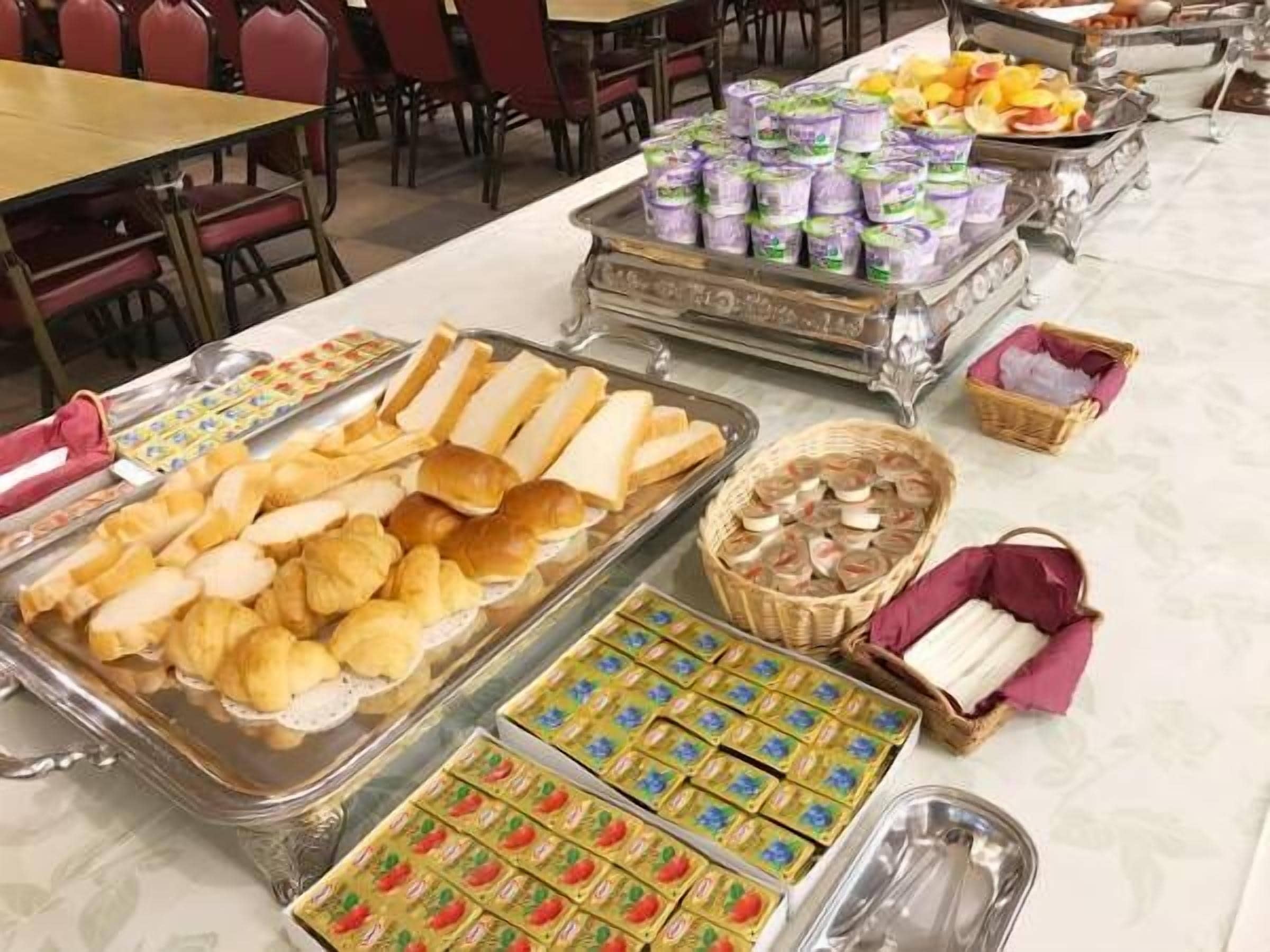 Un bufé con diversas opciones de comida, como pan, pasteles y postres.