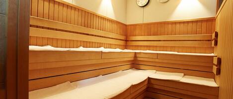 A sauna with wooden benches and two wall-mounted clocks.