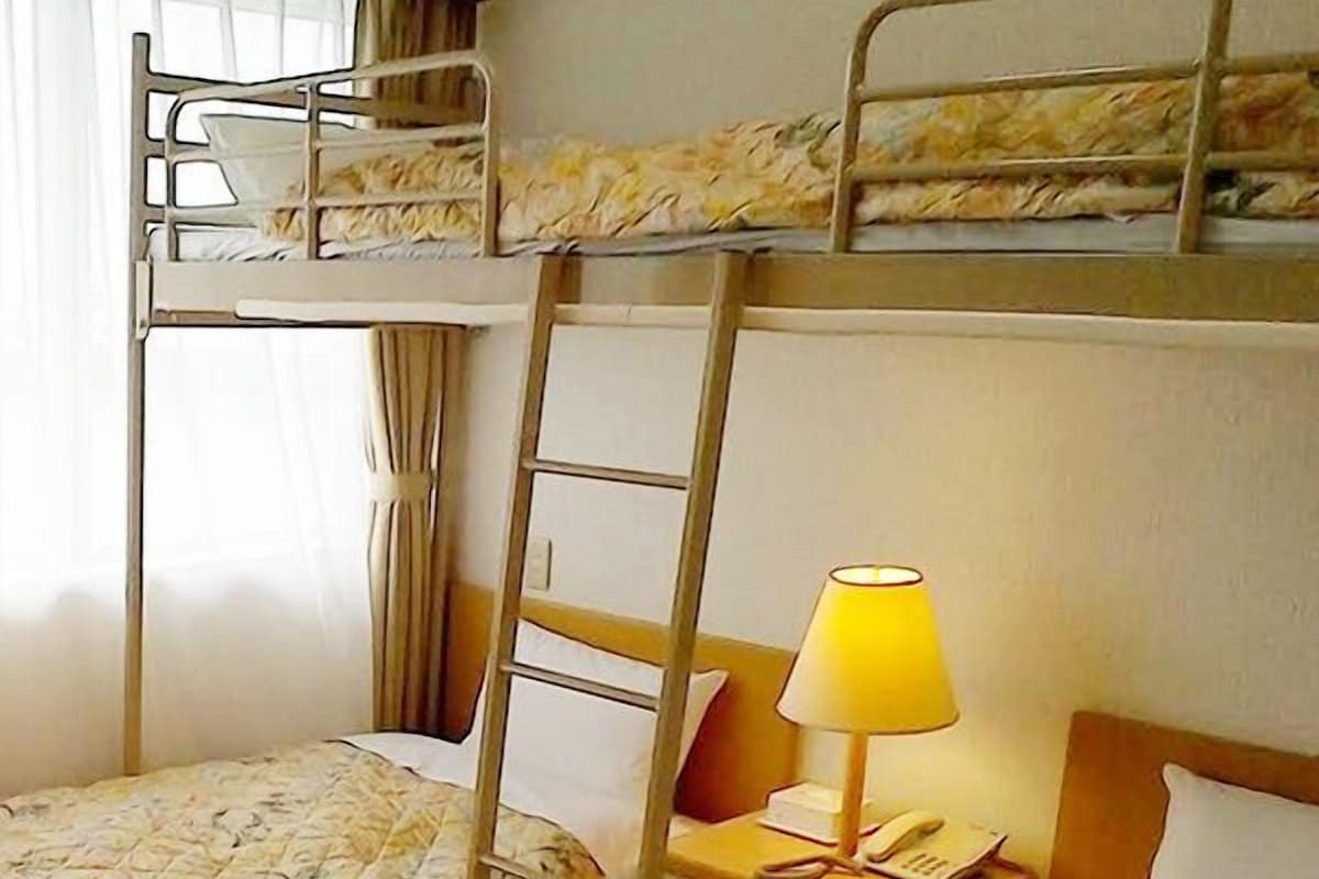 A bunk bed room with a ladder, a bedside lamp, and a nightstand.