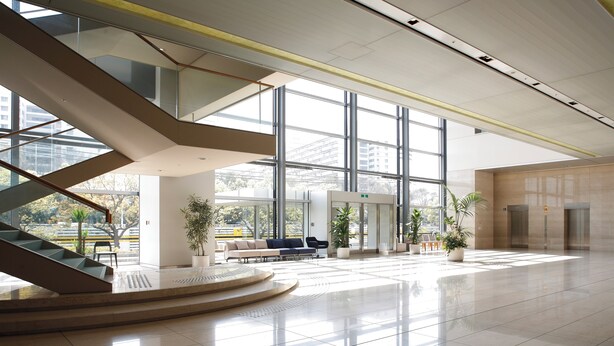 Eine geräumige Lobby mit moderner Treppe, großen Fenstern und Sitzbereichen.