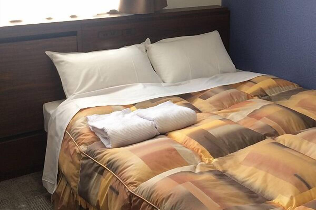 A hotel room with a bed, curtains, and a window.