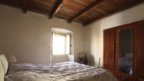 Une chambre dotée d’un grand lit, d’une armoire en bois et d’une fenêtre laissant entrer la lumière naturelle.