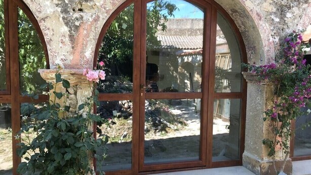 Un bâtiment rustique en pierre, doté de fenêtres en arc de cercle et d’un banc devant l’entrée.