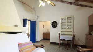Une pièce comprenant un lit, une table avec des chaises, un jeu de fléchettes et un meuble avec des étagères.