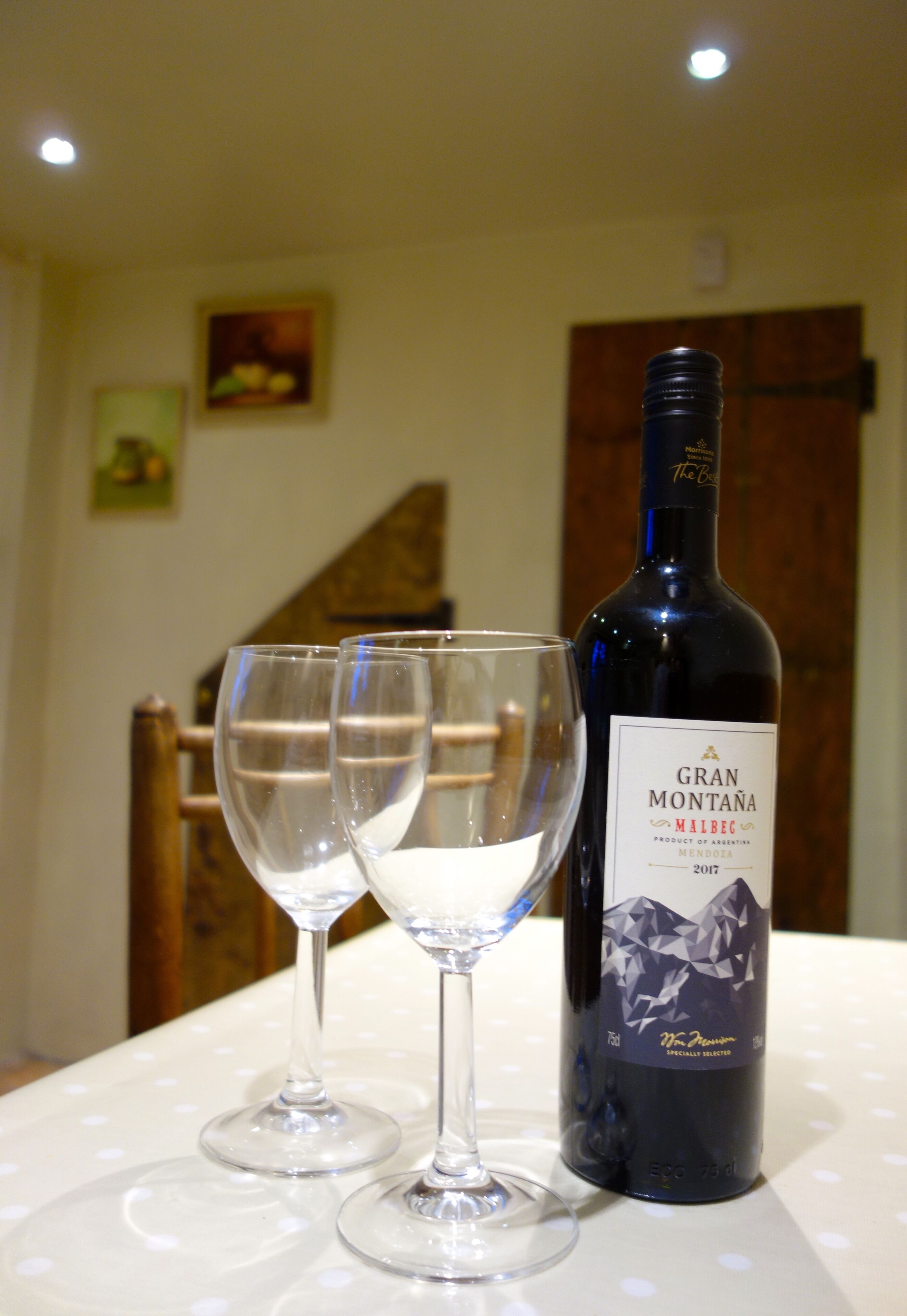 Una botella de vino Gran Montana y dos copas de vino vacías sobre una mesa.