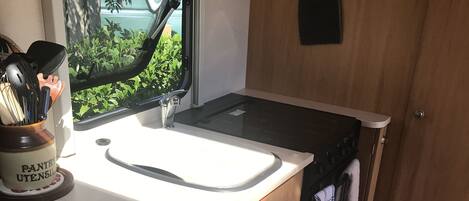 A compact kitchen with a sink, stove, and wooden cabinets.