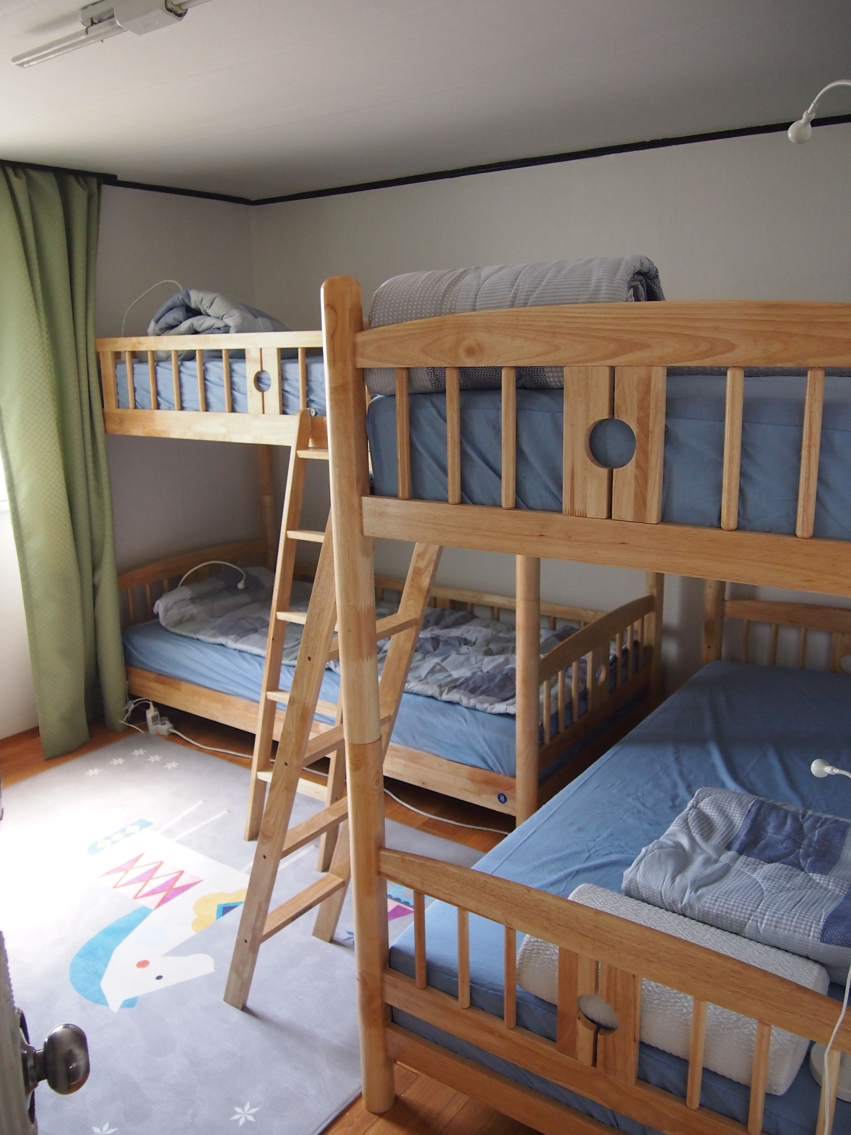 A bunk bed room with a ladder, wooden headboard, and a grey floor mat with a cartoon character.