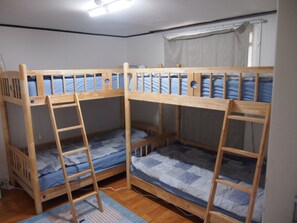 A room with three bunk beds, each with a ladder, wooden headboard, and blue bedding. - GUESTHOUSE 345 - Hostel (Seoul)