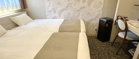A hotel room with two beds, a desk, a chair, and a large speaker.