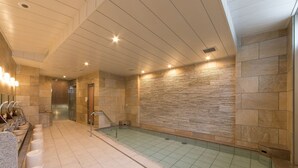 A modern indoor swimming pool with a tiled floor and a stone wall. - S Training Center Hotel Osaka (Osaka)