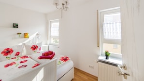 A bedroom with a bed, a radiator, a window, and a door.