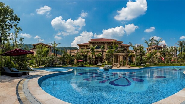 A swimming pool with a mosaic design, surrounded by palm trees and lounge chairs. - Felton Grand Hotel Bazhong (Bazhong)