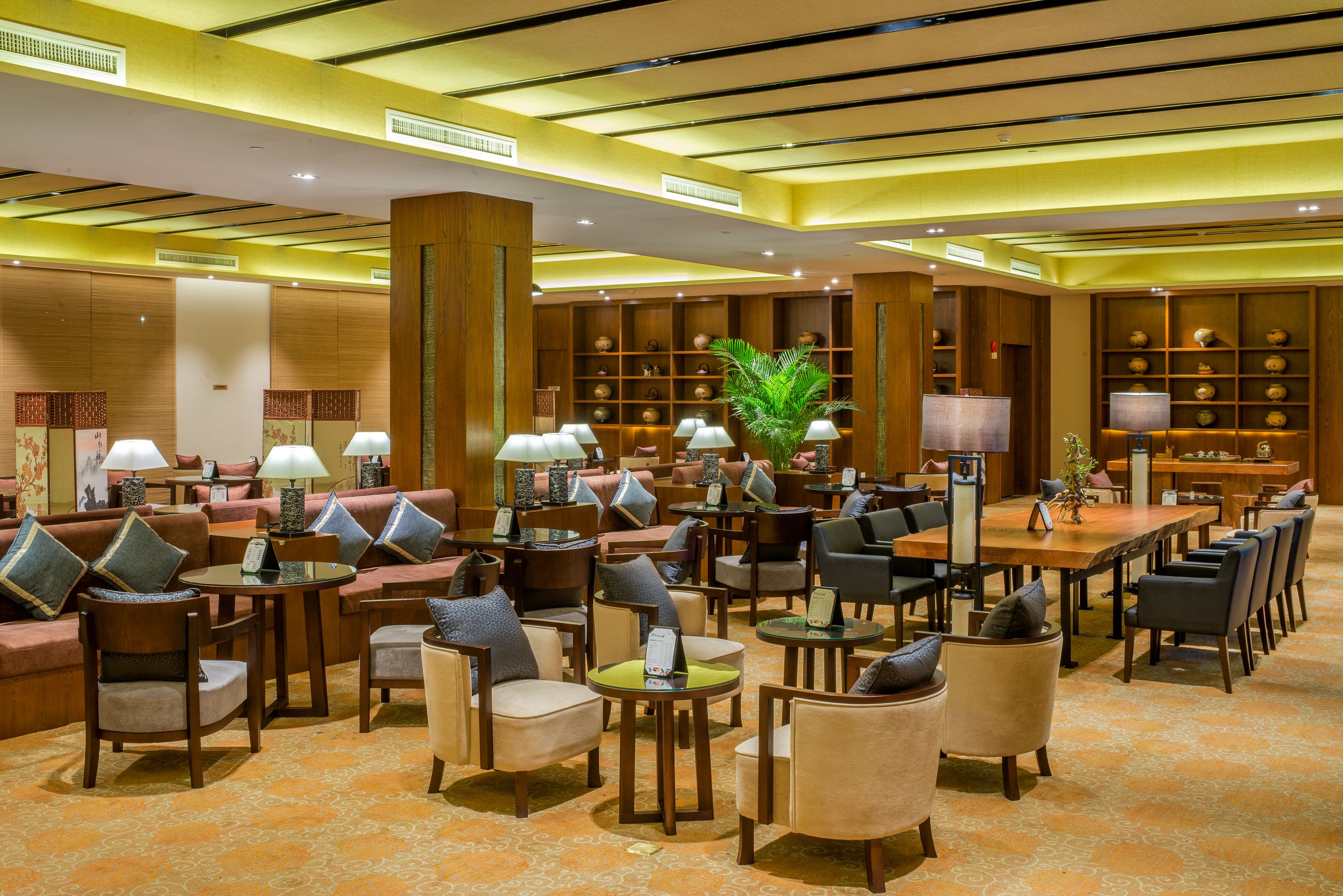 A spacious lobby with multiple seating areas, including sofas and chairs, and a central dining table.
