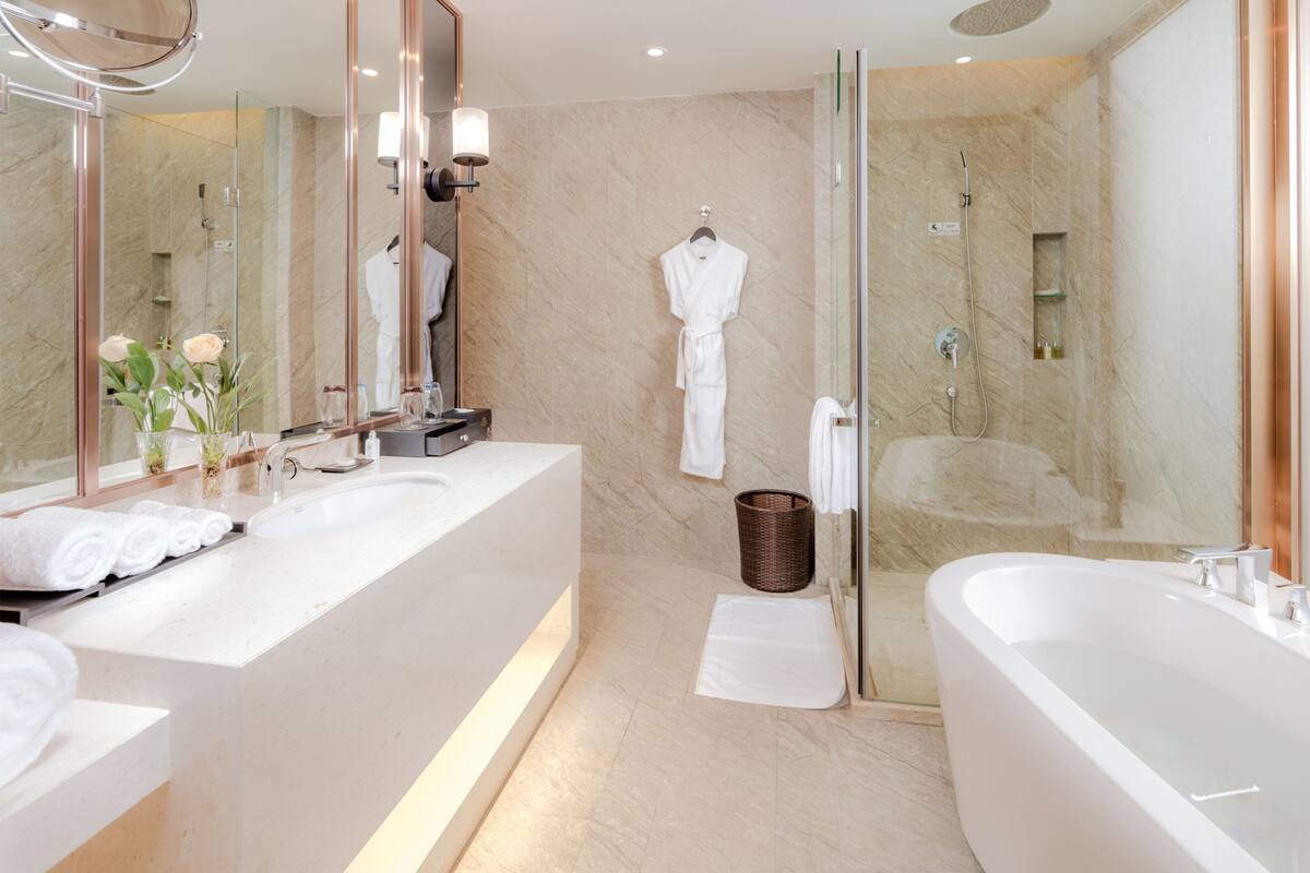 Ein modernes Badezimmer mit einer großen Badewanne, einer separaten Duschkabine und einem Waschtisch mit Spiegel und Waschbecken.