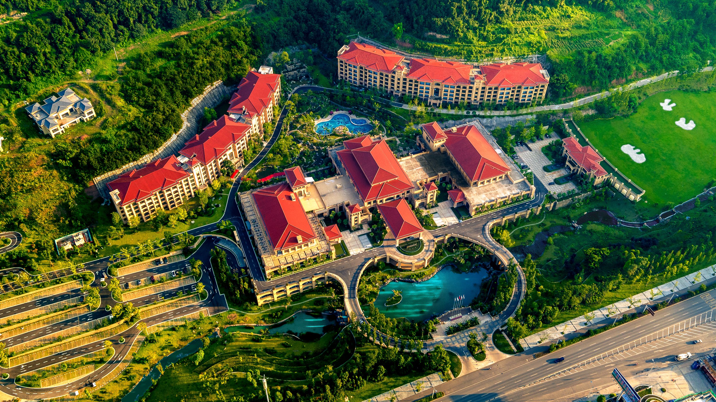 An aerial view of a resort with multiple buildings, a swimming pool, and a winding road.
