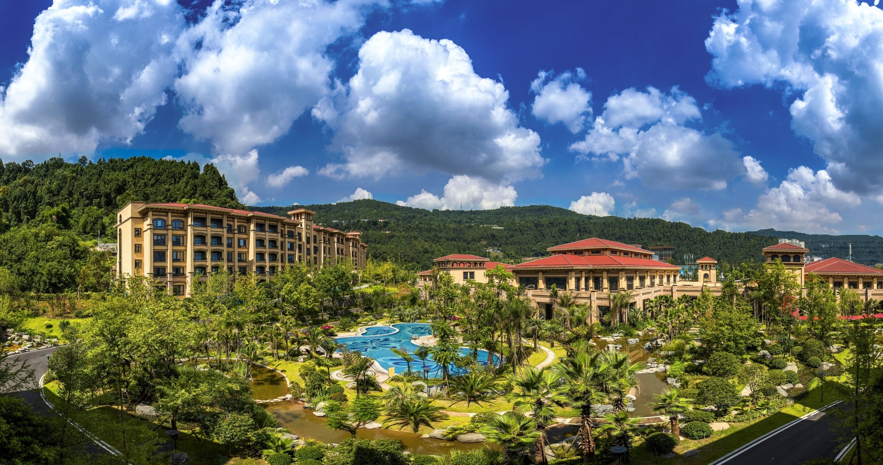 A resort with multiple buildings, a swimming pool, and lush greenery.