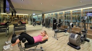 Een fitnessruimte met diverse trainingsapparaten, waaronder een bankdrukpers, gewichten en cardioapparatuur.