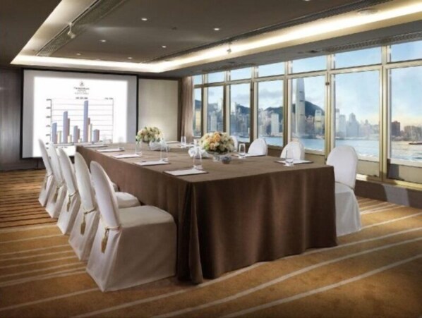 A conference room with a large table, white chairs, and a city view through large windows. - The Royal Pacific Hotel & Towers (Kowloon)