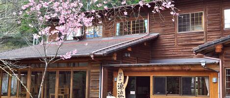 A wooden cabin with large windows, a wooden sign, and a bench outside.