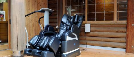 A massage chair in a wooden room with a large window.