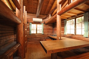 A log cabin interior with a wooden table, a window with curtains, and an air conditioning unit. - Nature Resort in Shimanto (Nakatosa)