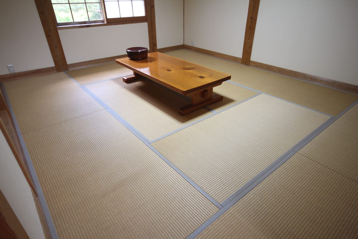 Una habitación con tatami, una mesa de madera y un cuenco pequeño.