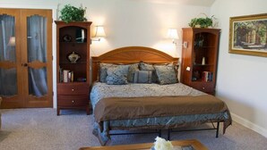 A bedroom with a large bed, two nightstands, a wooden wardrobe, and a painting on the wall. - LV5 Upper Floor Suite (La Verkin)