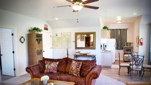 A living room with a sofa, coffee table, and dining area. - LV5 Upper Floor Suite (La Verkin)