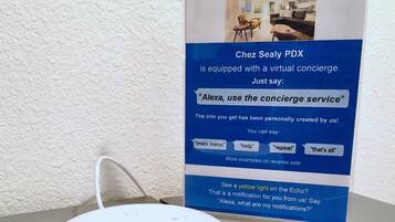 A white speaker device on a table with a sign about a virtual concierge service.
