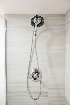 A shower with a handheld showerhead and a fixed wall-mounted showerhead in a bathroom with light-colored tiled walls. - ★ CLEAN ★ NEAR DOWNTOWN + PRIVATE PATIO ★ WALKABLE (Portland)