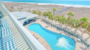Área da piscina com espreguiçadeiras e vista para a praia.