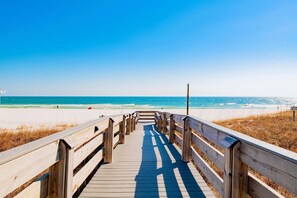 A wooden boardwalk leading to a beach with a clear blue sky.