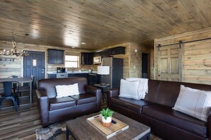 Un interior de cabaña con comedor, cocina y dos sofás.
