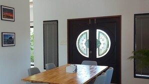 A conference room with a wooden table and six chairs, a large door with a stained glass window, and two framed pictures on the wall. - Ton Yaang Private Pool Villa (Krabi)