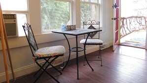 A room with a table and two chairs, a window, and an air conditioning unit. - CLOSE TO DOWNTOWN- The Peacock Retreat- Dogs Stay Free  (Asheville)