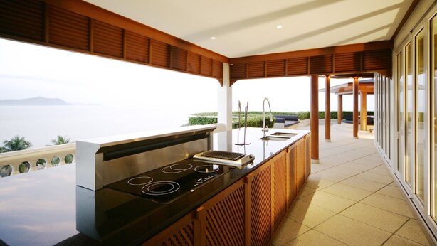 A modern kitchen with an island, a view of the sea, and a balcony with a seating area. - BaanSomprasong Condo Pattaya by Songland (Sattahip)