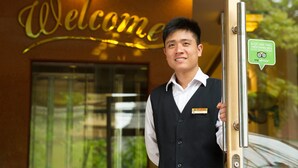 A person standing in front of a reception desk with a 'Welcome' sign above. - Thuy Anh Hotel (Ninh Binh)