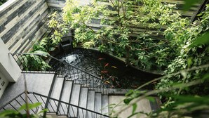 A staircase leading to a koi pond surrounded by lush greenery. - Babylon Garden Condotel (Da Nang)